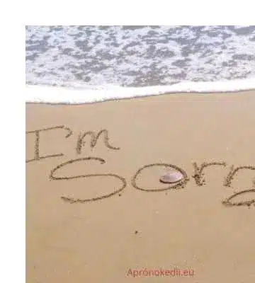 Sajnálom idézetek. A homokban az "I'm sorry" felirat látható, a tenger hullámai közelében.