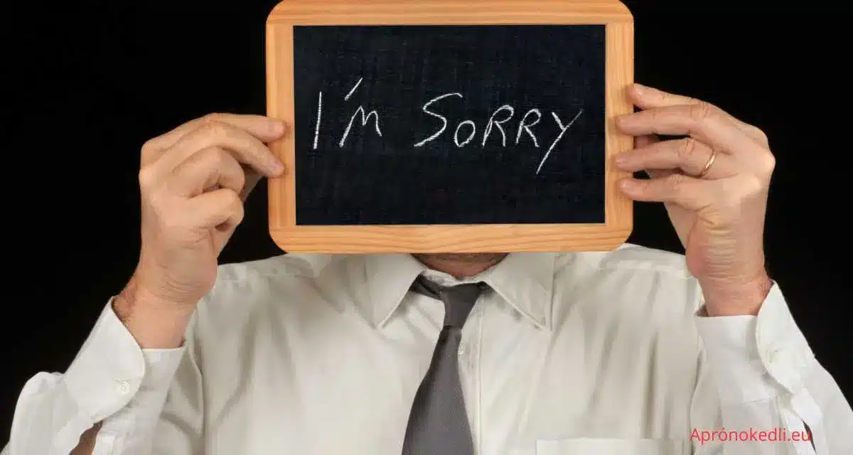 Sajnálom idézetek. Egy férfi tart egy kis táblát a kezében, amelyen az "I'm sorry" felirat szerepel, és ezzel takarja az arcát.