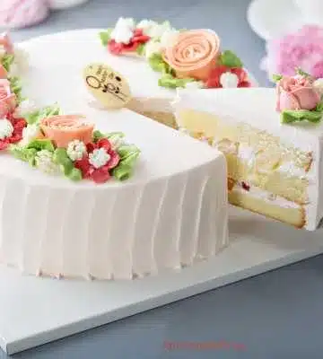 A negyedik képen egy fehér torta látható, amely virágokkal van díszítve. Ez a torta valószínűleg egy habos, könnyed sütemény, amelyet ünnepi alkalmakra készítettek.