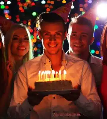 Szülinapi kép férfiaknak. A negyedik képen egy szülinapi tortát tartó fiatal férfi látható, aki körül barátai állnak. A tortán égő gyertyák vannak, és mindenki mosolyogva néz a kamerába. Az ünneplés hátterében színes fények láthatók, ami hangulatossá teszi a jelenetet.